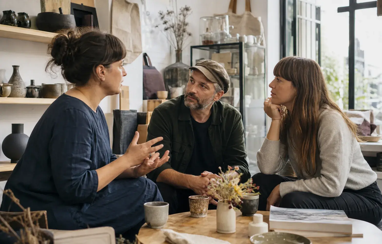 A business owner listens closely to two customers during an informal conversation in an independent shop.